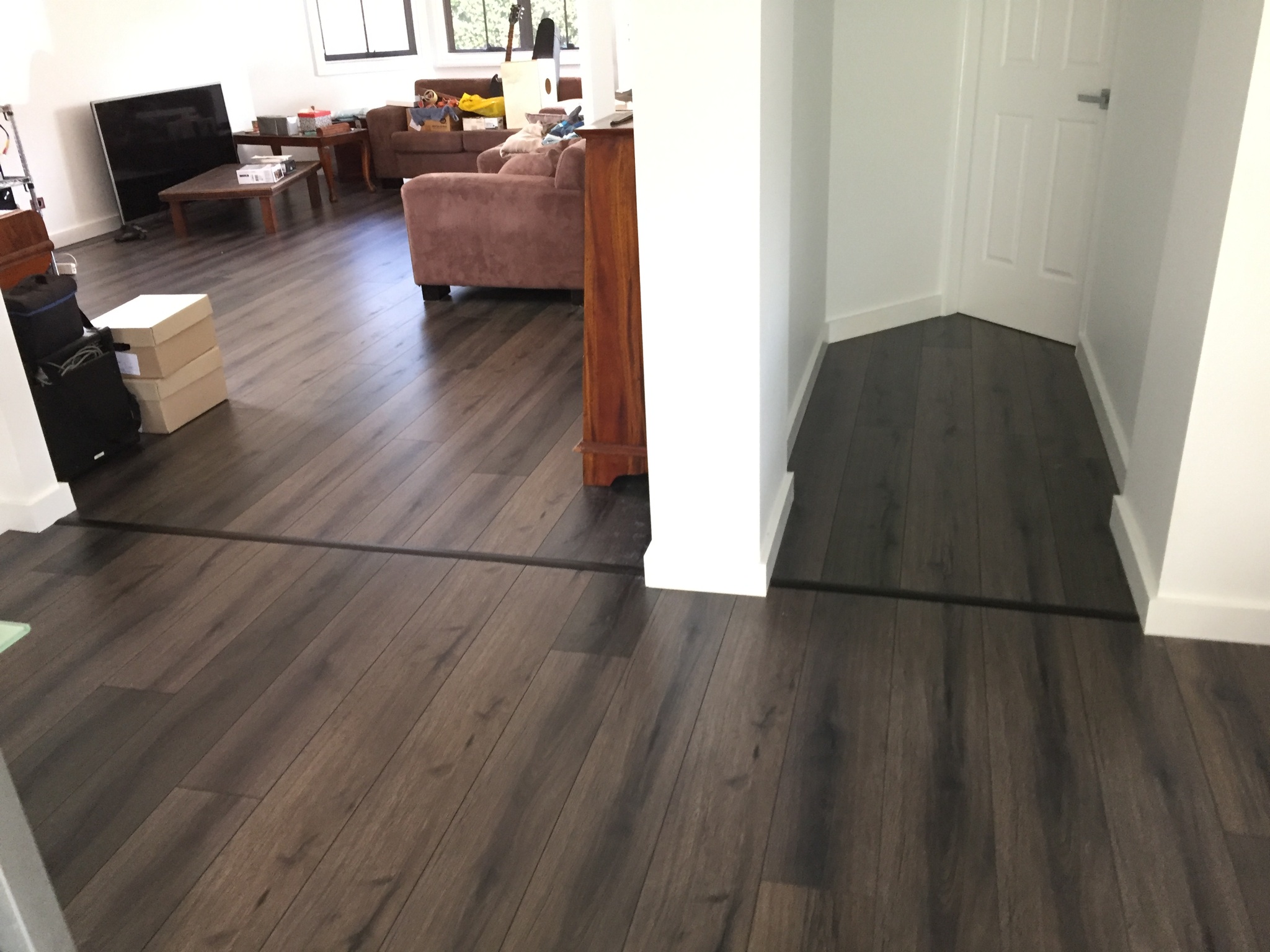 Dark timber-look laminate flooring laid through a living room into a hallway
