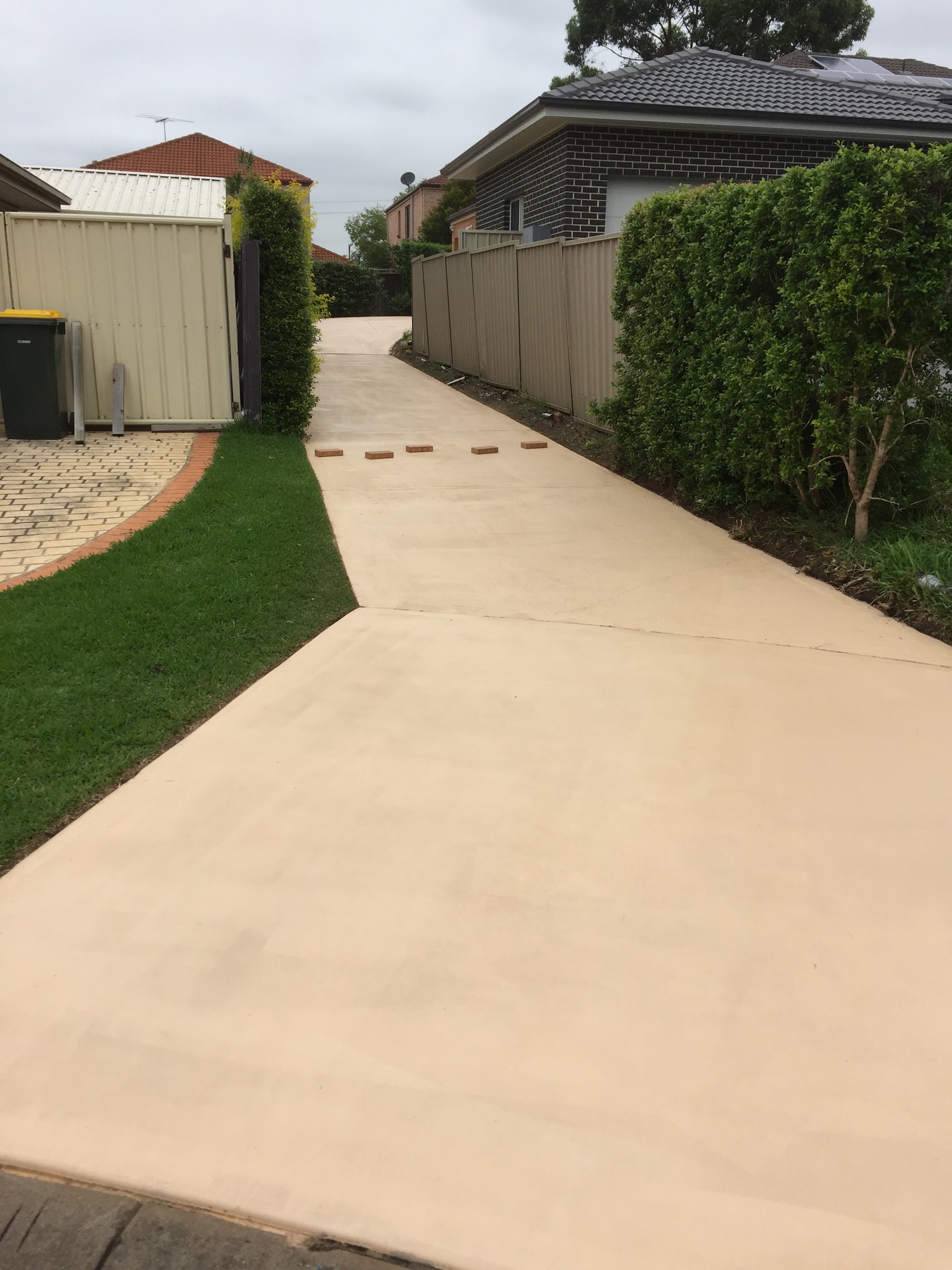 Freshly finished concrete path running down the side of a house to the back yard
